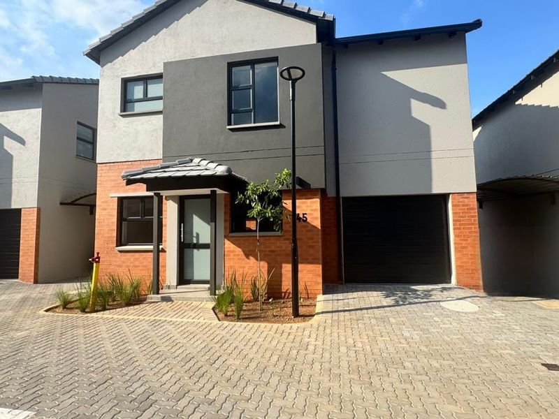 Modern double-story residential home featuring a brick and plaster facade, paved driveway, and an integrated garage.