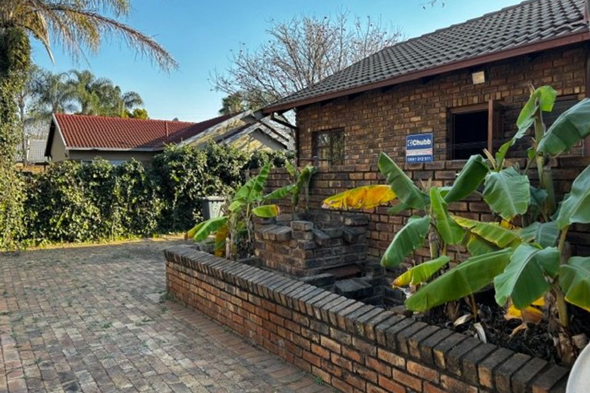Rear exterior area featuring a brick-paved patio, a built-in brick braai, and a face brick facade with a tiled roof.