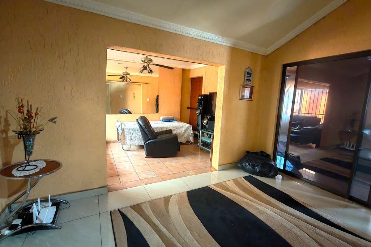 Living room area featuring textured walls, crown molding, tiled flooring, and a sliding glass door leading to an adjacent space.
