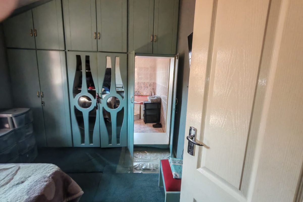 Bedroom featuring extensive built-in cupboards with integrated mirror panels and direct access to an en-suite bathroom.