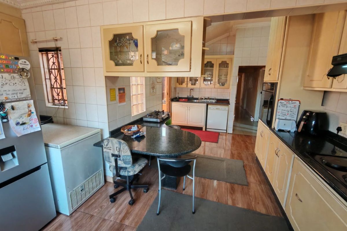 A functional kitchen featuring granite countertops, tiled backsplash, built-in cabinetry, and a breakfast nook area with tiled flooring throughout.