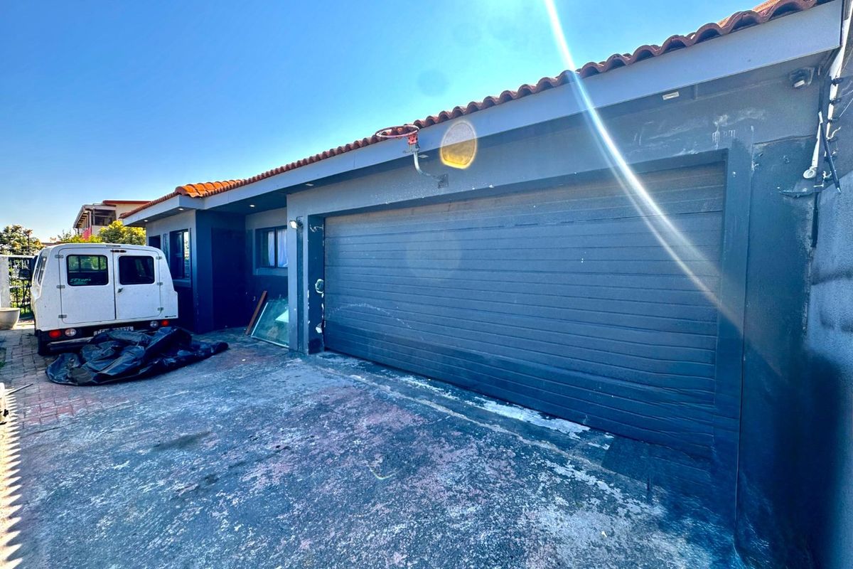 Front exterior view of the property featuring a garage with a dark finish, tiled roof, and a paved driveway area.