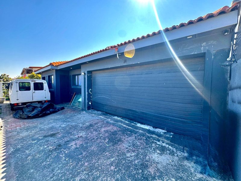 Front exterior view of the property featuring a garage with a dark finish, tiled roof, and a paved driveway area.