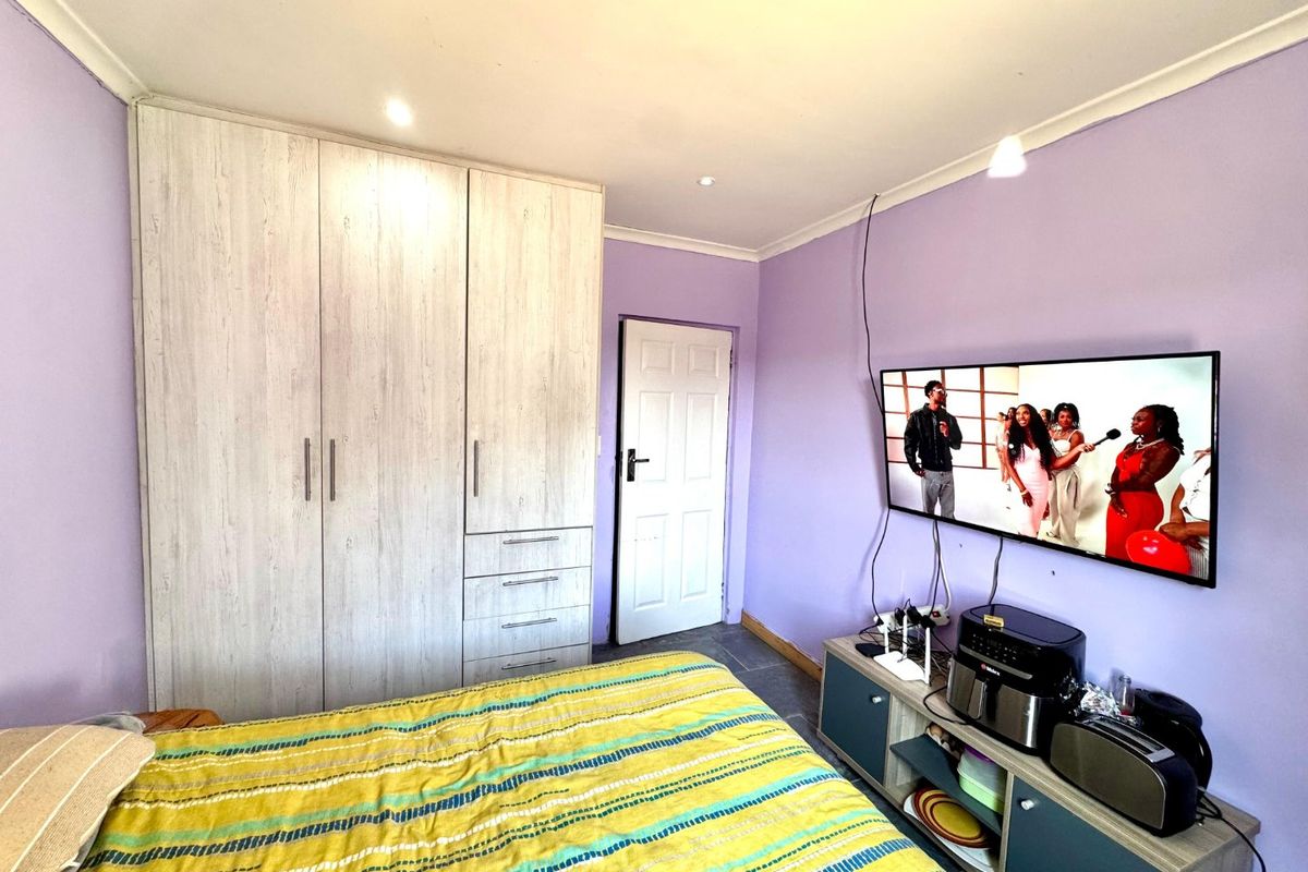 A bedroom featuring built-in wardrobes with light wood-grain finish, recessed downlighting, and purple painted walls.