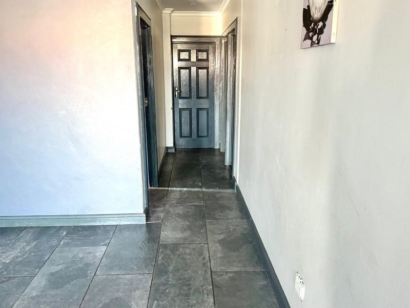 A functional hallway featuring dark tiled flooring and multiple internal doors, providing access to various rooms within the home.