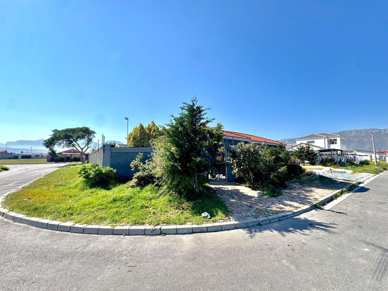 Street view of the property showing the corner lot, perimeter wall with electric fencing, and paved driveway access.