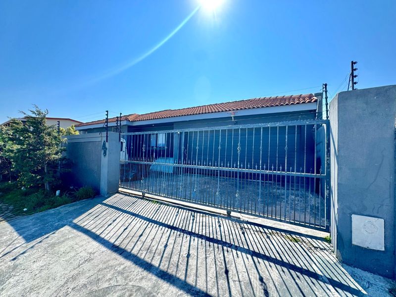 Front exterior view of the property featuring a secure metal gate, perimeter wall with electric fencing, and a tiled roof.