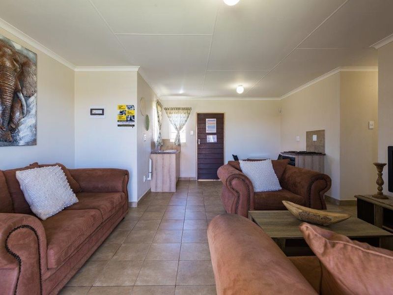 Open-plan living area featuring tiled flooring, a compact kitchen corner with built-in cabinetry, and a functional layout suitable for comfortable living.