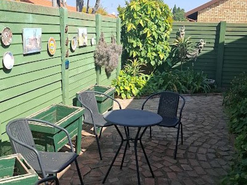 A private outdoor patio area featuring brick paving, timber fencing, and integrated wooden planters, offering a cozy space for outdoor relaxation.
