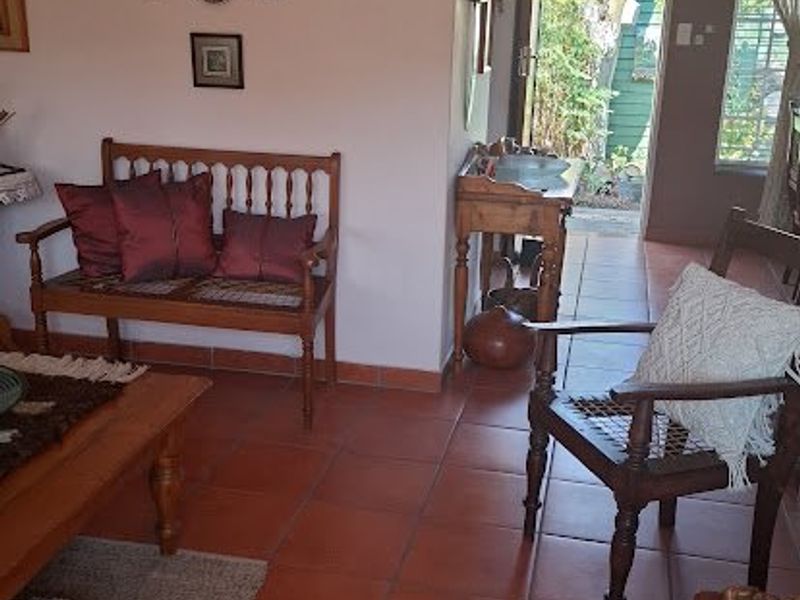 A living room area featuring terracotta floor tiles and a coved ceiling, with direct access to an outdoor space.