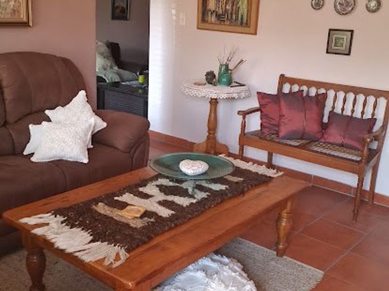 A cozy living room featuring terracotta floor tiles and a distinctive arched doorway leading to an adjacent space.