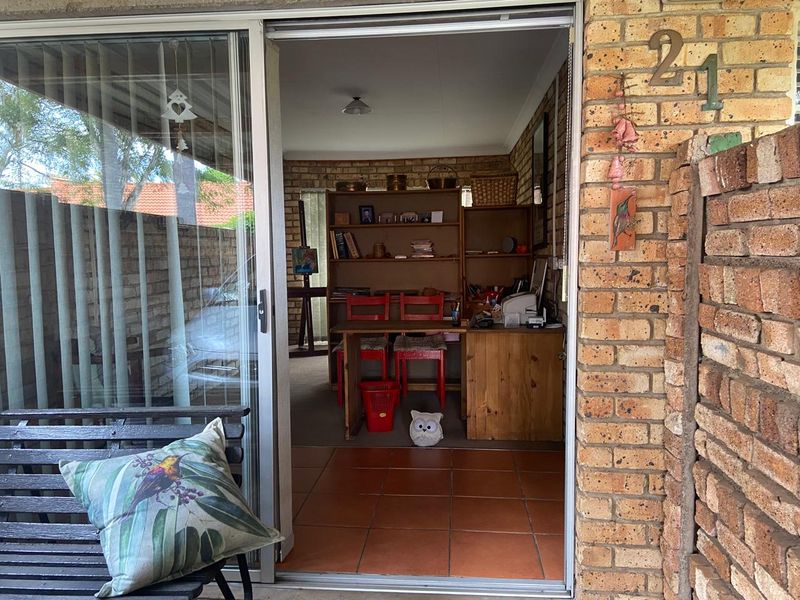 A covered patio area featuring exposed brick walls and tiled flooring, providing a transition space between the exterior and the interior living area.