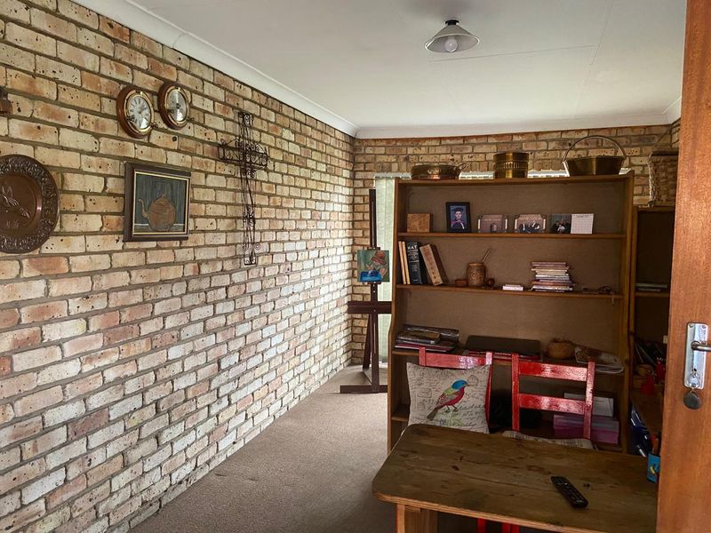 A living area featuring a distinctive exposed brick wall, carpeted flooring, and classic cove cornice detailing.