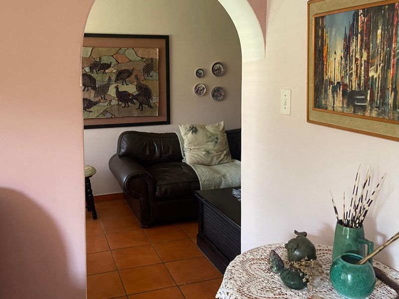 A view through an arched doorway into a living area featuring terracotta floor tiles and neutral wall finishes.