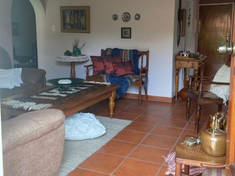 A living room featuring traditional terracotta floor tiles and an arched entryway leading to adjacent living spaces.