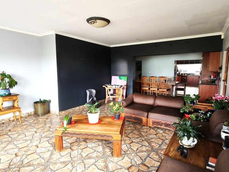 Open plan living and dining area featuring stone-look tiled flooring and a connected kitchen space with wooden cabinetry.