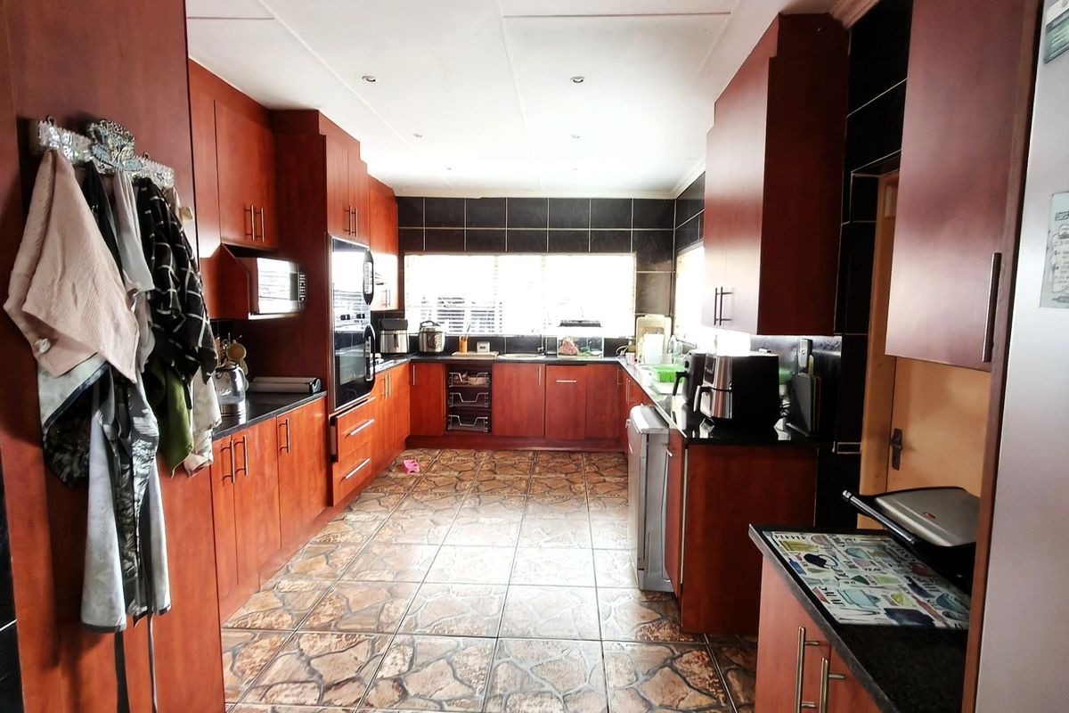 A functional kitchen featuring dark wood cabinetry, granite countertops, tiled flooring, and built-in appliances, offering a classic layout with ample storage space.