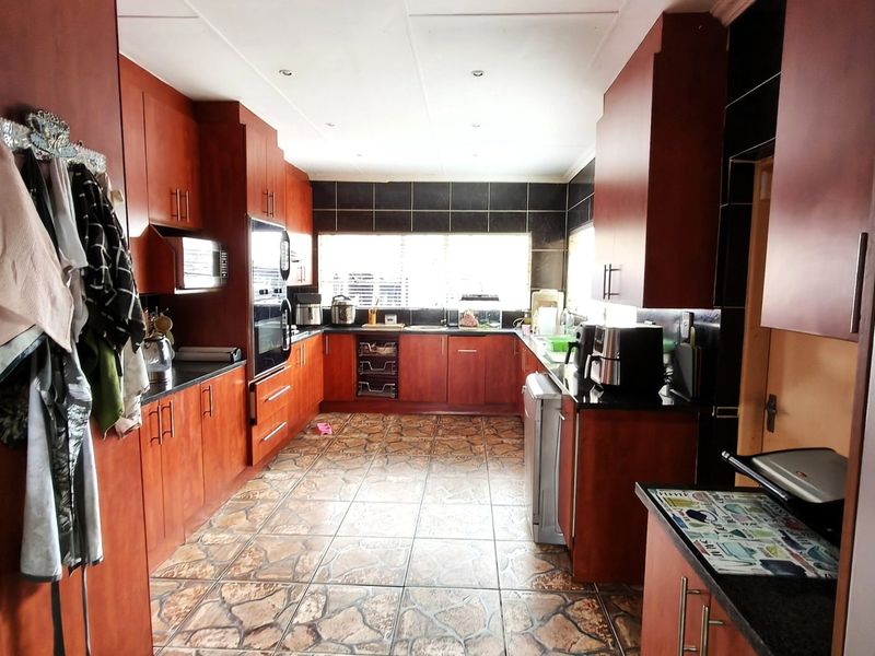 A functional kitchen featuring dark wood cabinetry, granite countertops, tiled flooring, and built-in appliances, offering a classic layout with ample storage space.
