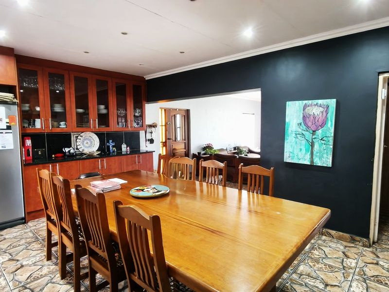 Open-plan dining and kitchen area featuring wooden cabinetry, stone countertops, and tiled flooring, creating a functional space for family meals and entertaining.
