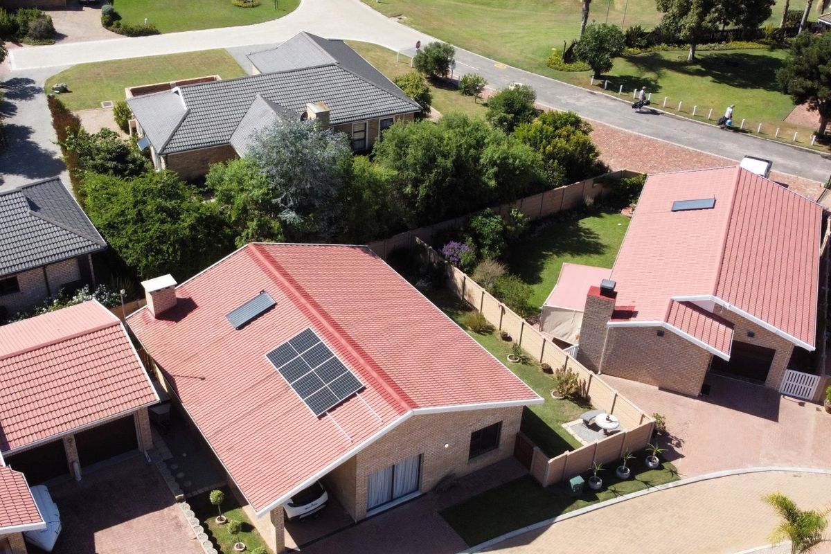 Aerial view of a residential property featuring a tiled roof with integrated solar panels and a solar geyser, set within a landscaped estate.