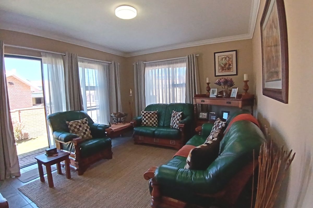 A comfortable living room featuring tiled flooring, cove cornicing, and large sliding glass doors that provide access to the outdoor area.