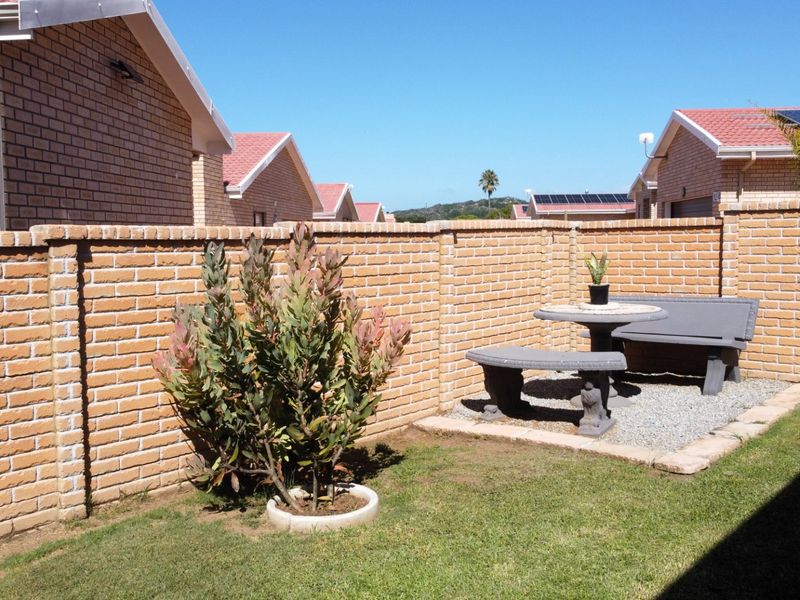 A private rear garden featuring a brick boundary wall, a gravel patio area, and a well-maintained lawn.