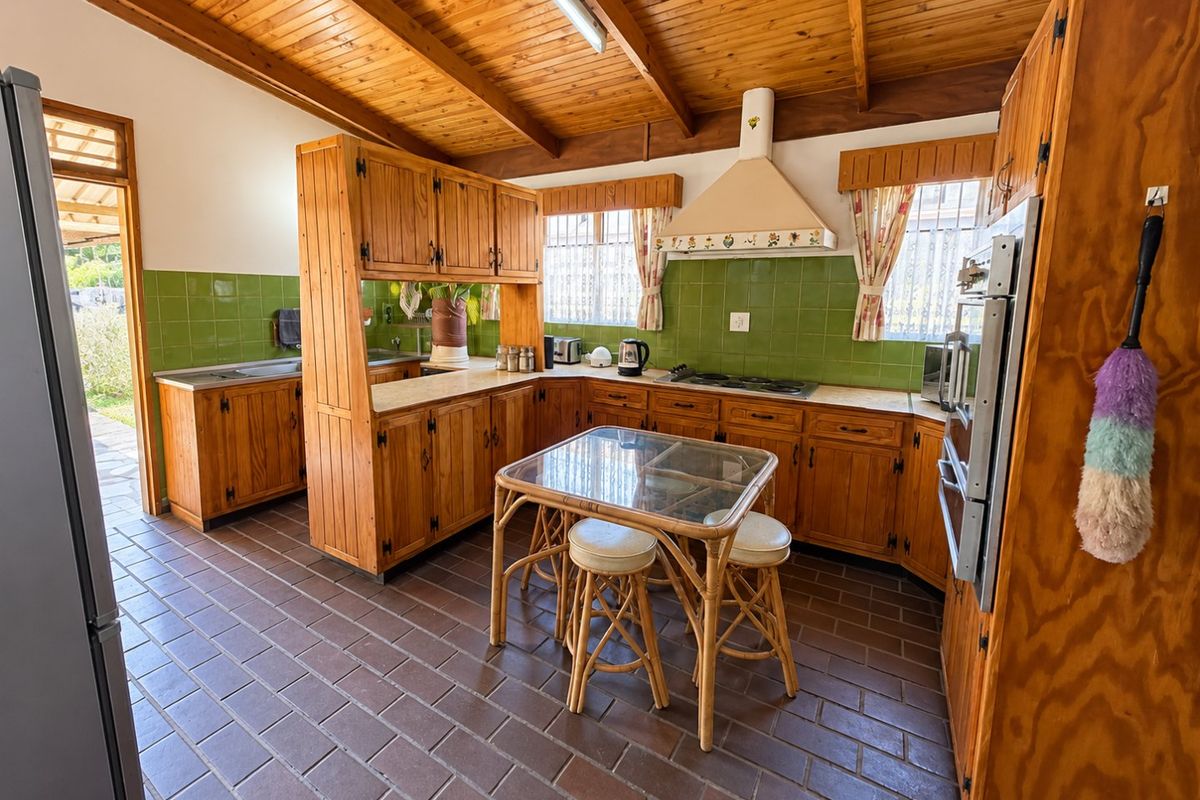 A rustic kitchen featuring timber cabinetry, exposed beam ceilings, tiled splashbacks, and built-in appliances, offering a traditional aesthetic with functional layout.