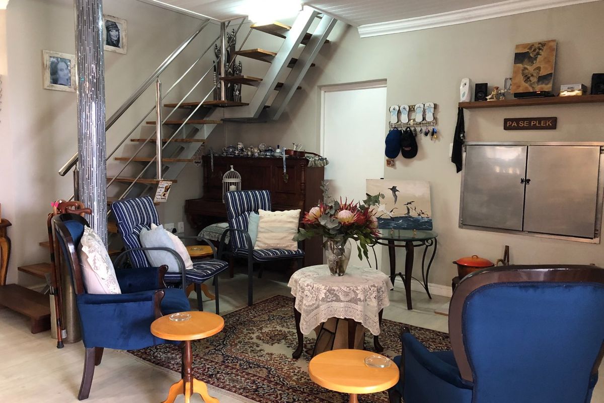 A living room featuring a modern staircase with stainless steel balustrades, tiled flooring, and a built-in wall cabinet.