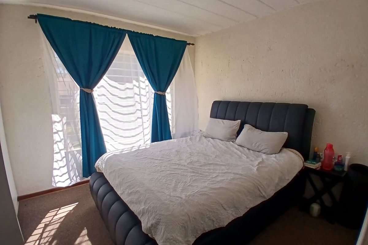 A standard bedroom featuring carpeted flooring and textured wall finishes, providing a functional space for rest.