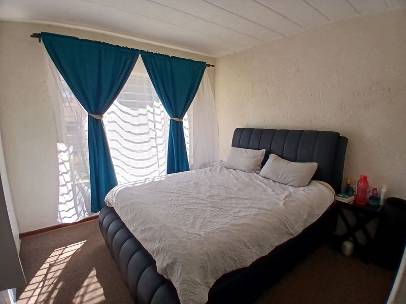 A standard bedroom featuring carpeted flooring and textured wall finishes, providing a functional space for rest.