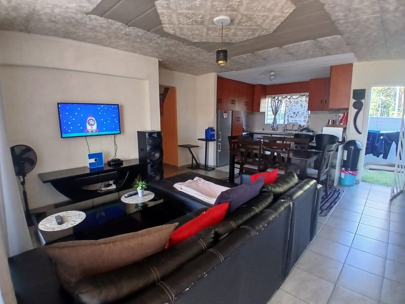 Open-plan living and kitchen area featuring tiled floors, textured ceiling, and functional built-in cabinetry.