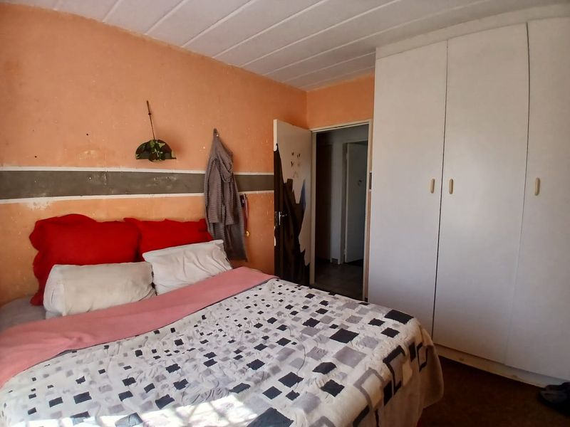 A bedroom featuring a built-in wardrobe and tongue and groove ceiling, currently requiring cosmetic updates to the wall finishes.