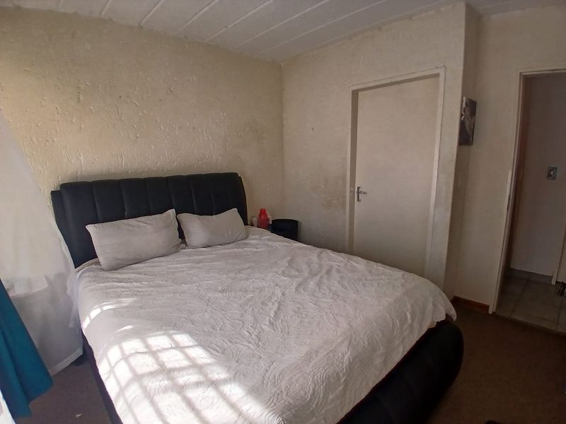 A bedroom featuring textured wall finishes and internal door access, currently showing signs of wear and surface staining requiring cosmetic attention.