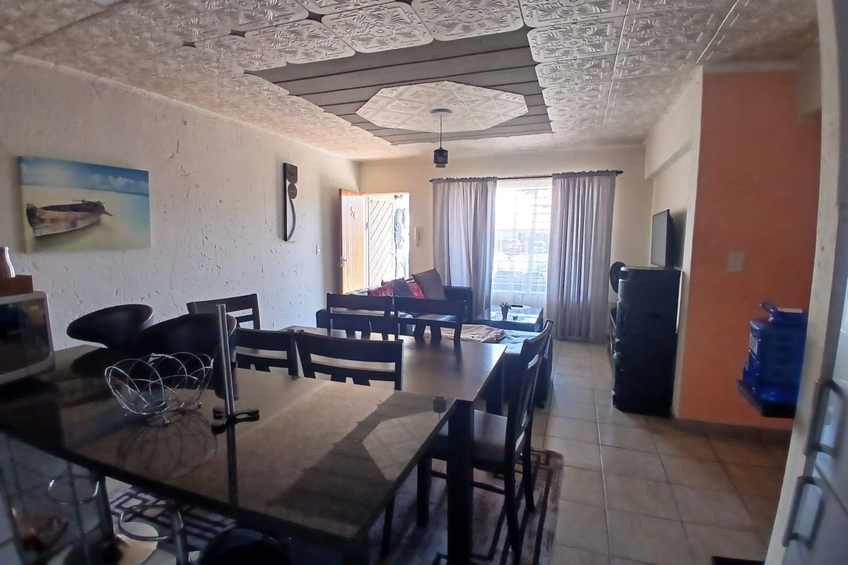 Open plan living and dining area featuring decorative ceiling tiles and tiled flooring, offering a versatile space for daily living.