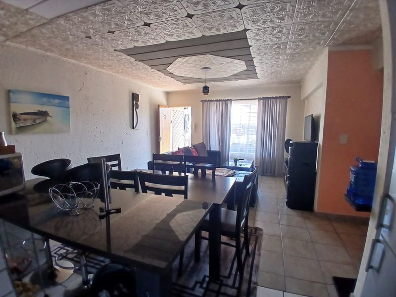 Open plan living and dining area featuring decorative ceiling tiles and tiled flooring, offering a versatile space for daily living.