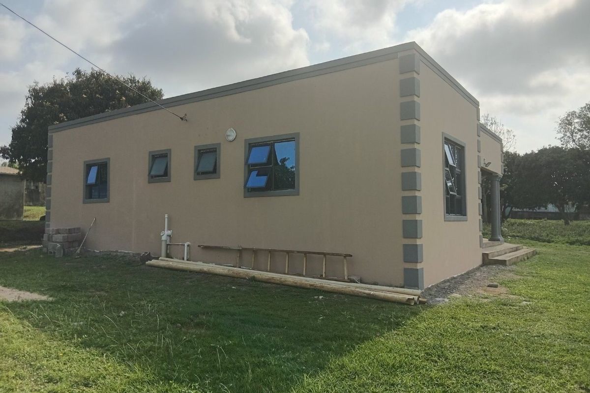 Exterior view of the property showing the side and rear facade with casement windows and concrete steps.