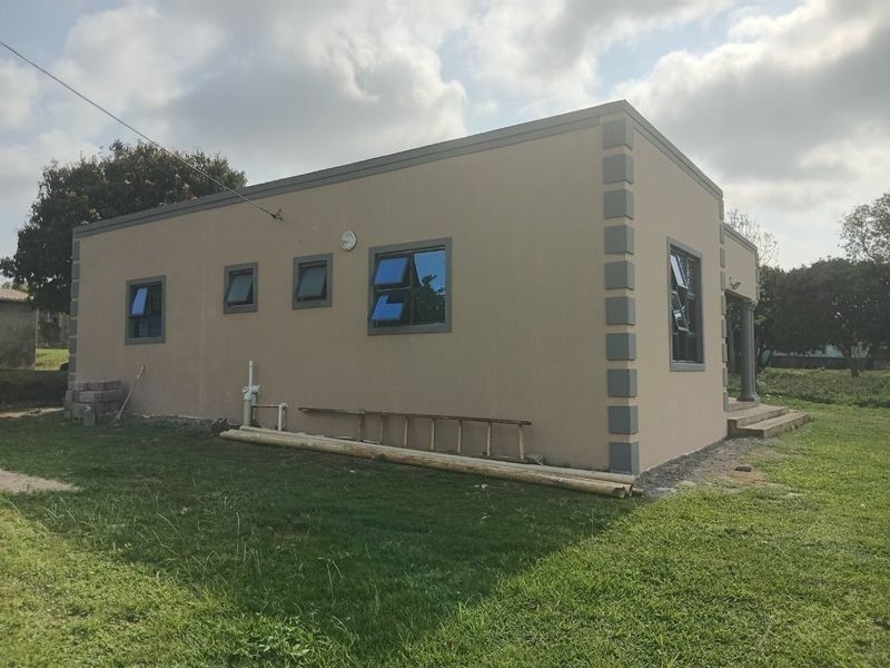 Exterior view of the property showing the side and rear facade with casement windows and concrete steps.