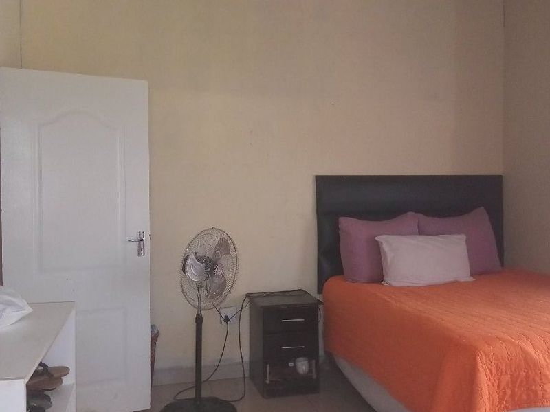 A bedroom featuring tiled flooring and an exposed timber rafter ceiling, requiring cosmetic updates to improve the overall finish and aesthetic appeal.