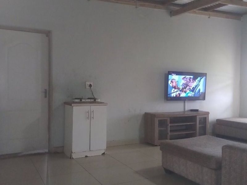 Living area featuring tiled flooring and an exposed timber beam ceiling with corrugated metal roofing.