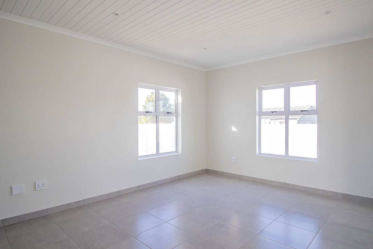 A bright, empty bedroom featuring neutral tiled flooring, clean white walls, and a modern tongue and groove ceiling with recessed lighting.