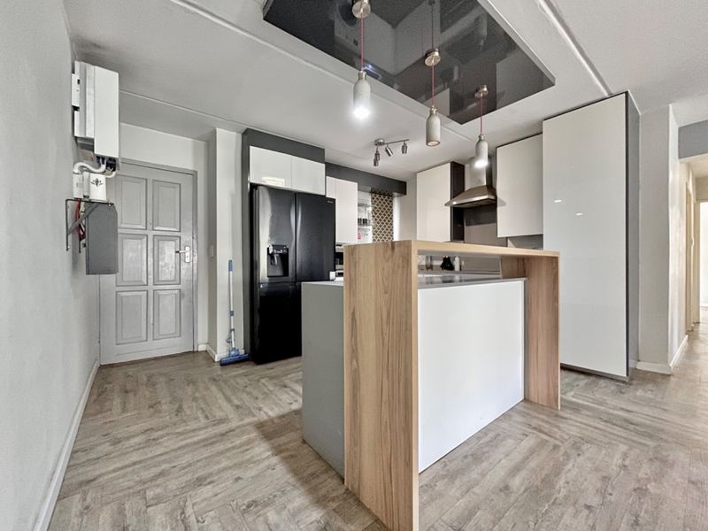 Modern kitchen featuring a central island, sleek cabinetry, and contemporary lighting fixtures, finished with durable laminate flooring.