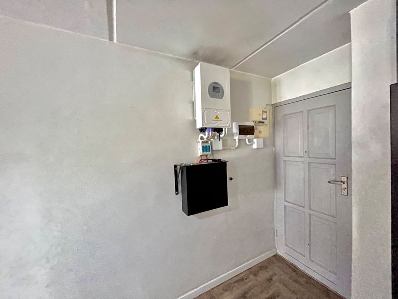 Utility area featuring a wall-mounted solar inverter and electrical distribution board, providing essential infrastructure for the property's power management.