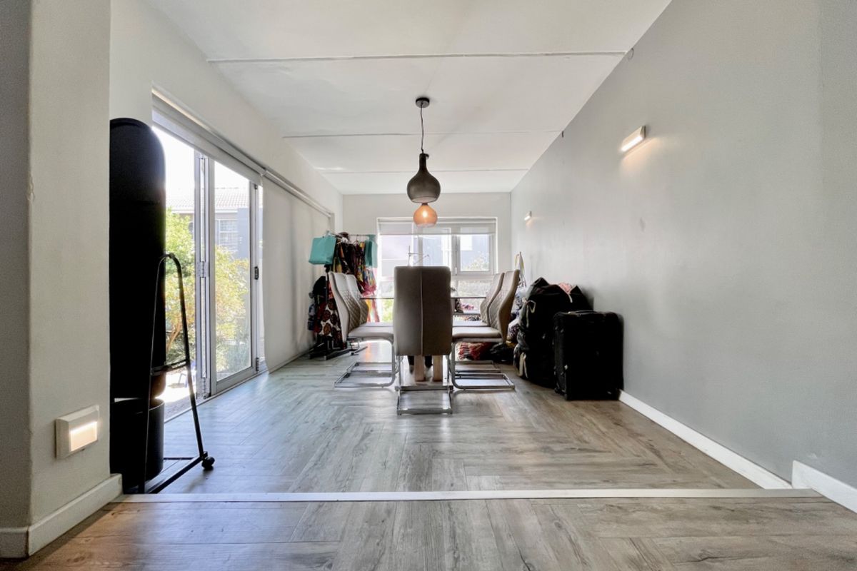 A living area featuring herringbone vinyl flooring, pendant lighting, and large sliding glass doors that provide access to the exterior.