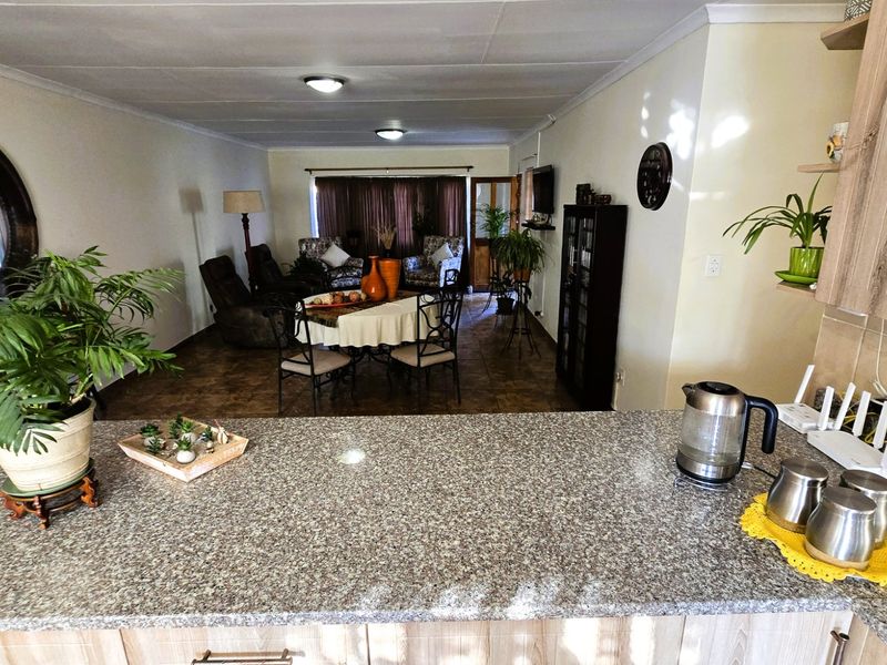 Open-plan living and dining area featuring a functional kitchen with granite countertops and tiled flooring, creating a cohesive and connected living space.