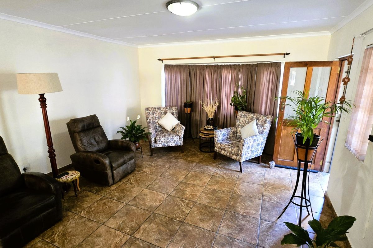 A living room featuring tiled flooring, a timber entrance door, and neutral wall finishes, providing a functional and well-lit space.