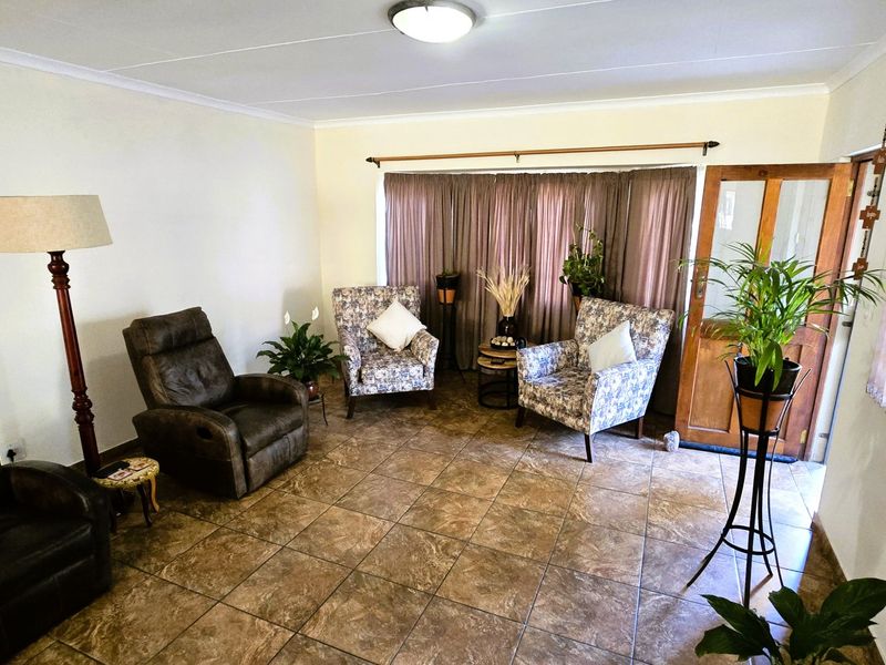 A living room featuring tiled flooring, a timber entrance door, and neutral wall finishes, providing a functional and well-lit space.