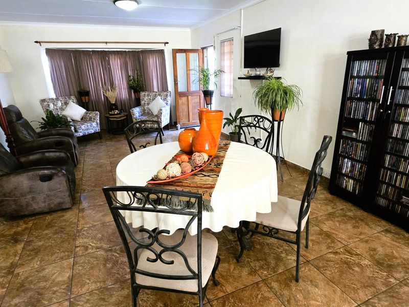 Open plan living and dining area featuring tiled flooring and direct access to the exterior through a timber door.