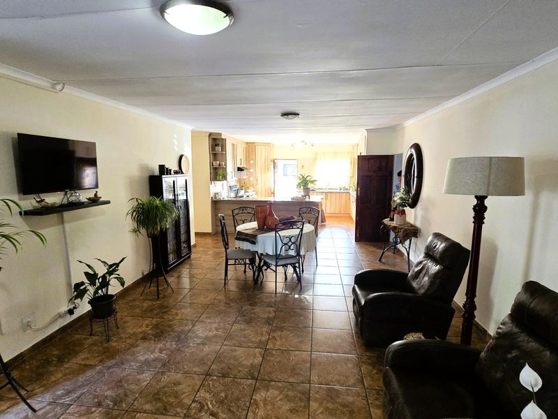 Spacious open-plan living and dining area flowing into a functional kitchen with tiled flooring throughout.
