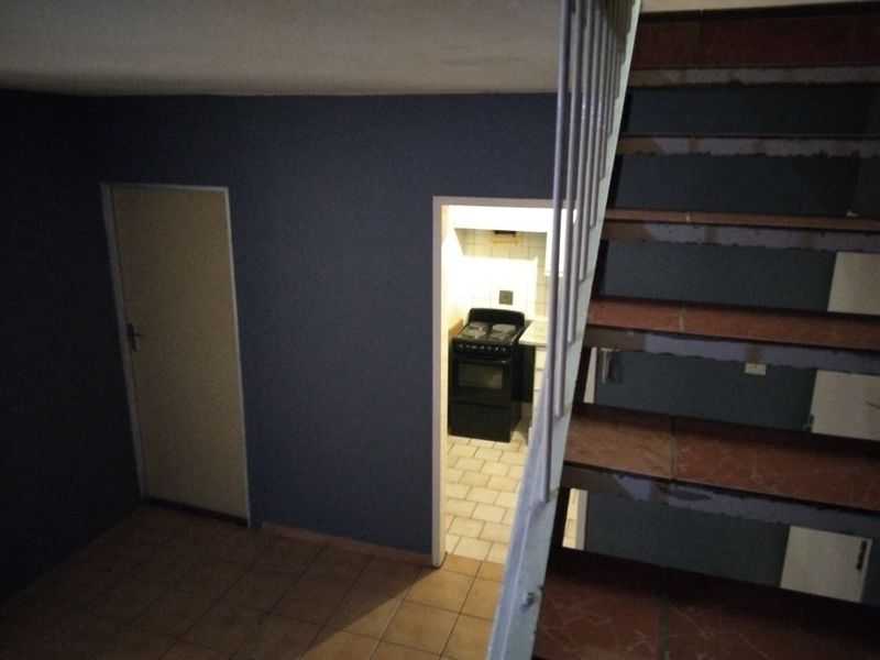 A view of a hallway featuring a staircase and a glimpse into a small kitchen area with a built-in stove.