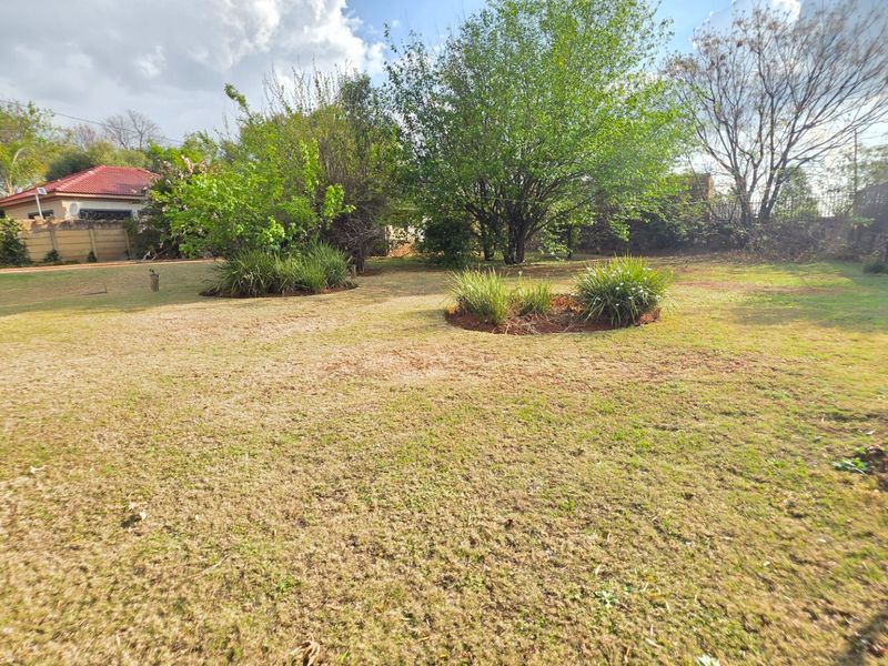 A spacious, established garden featuring mature trees, landscaped garden beds, and perimeter fencing, offering a private outdoor space.